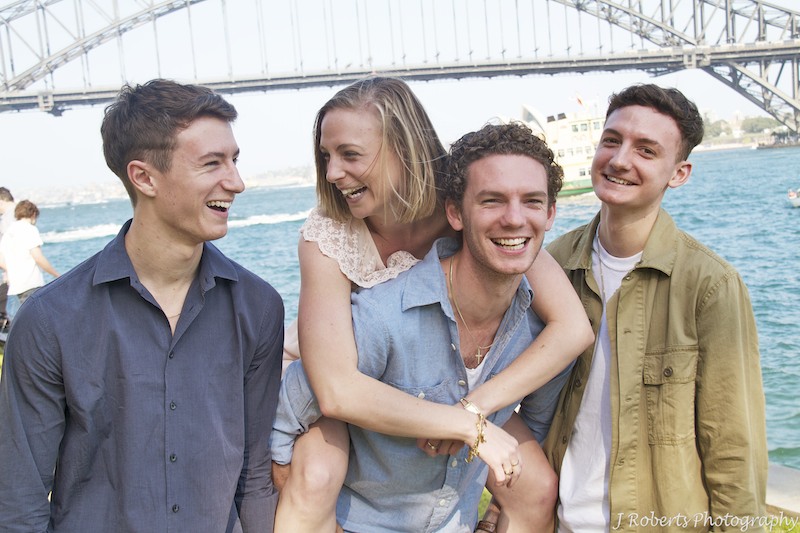 fun brothers and sisters piggyback shot in front of harbour bridge - Family Portrait Photography Sydney
